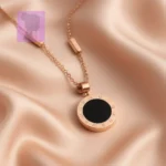Gold pendant necklace with black enamel inlay on soft pink satin fabric